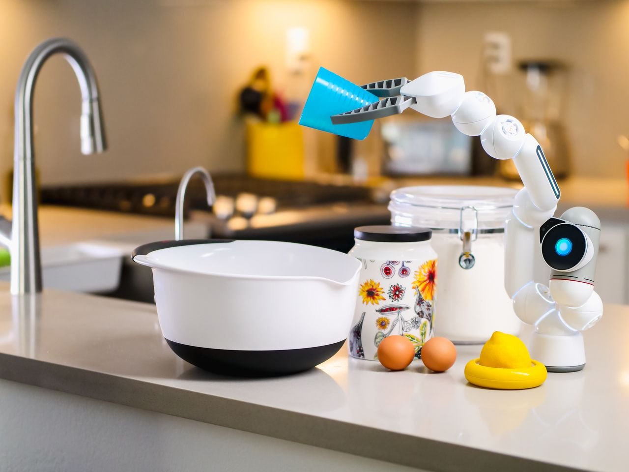 A robotic arm assists with mixing ingredients in a modern kitchen, showcasing advanced home technology.
